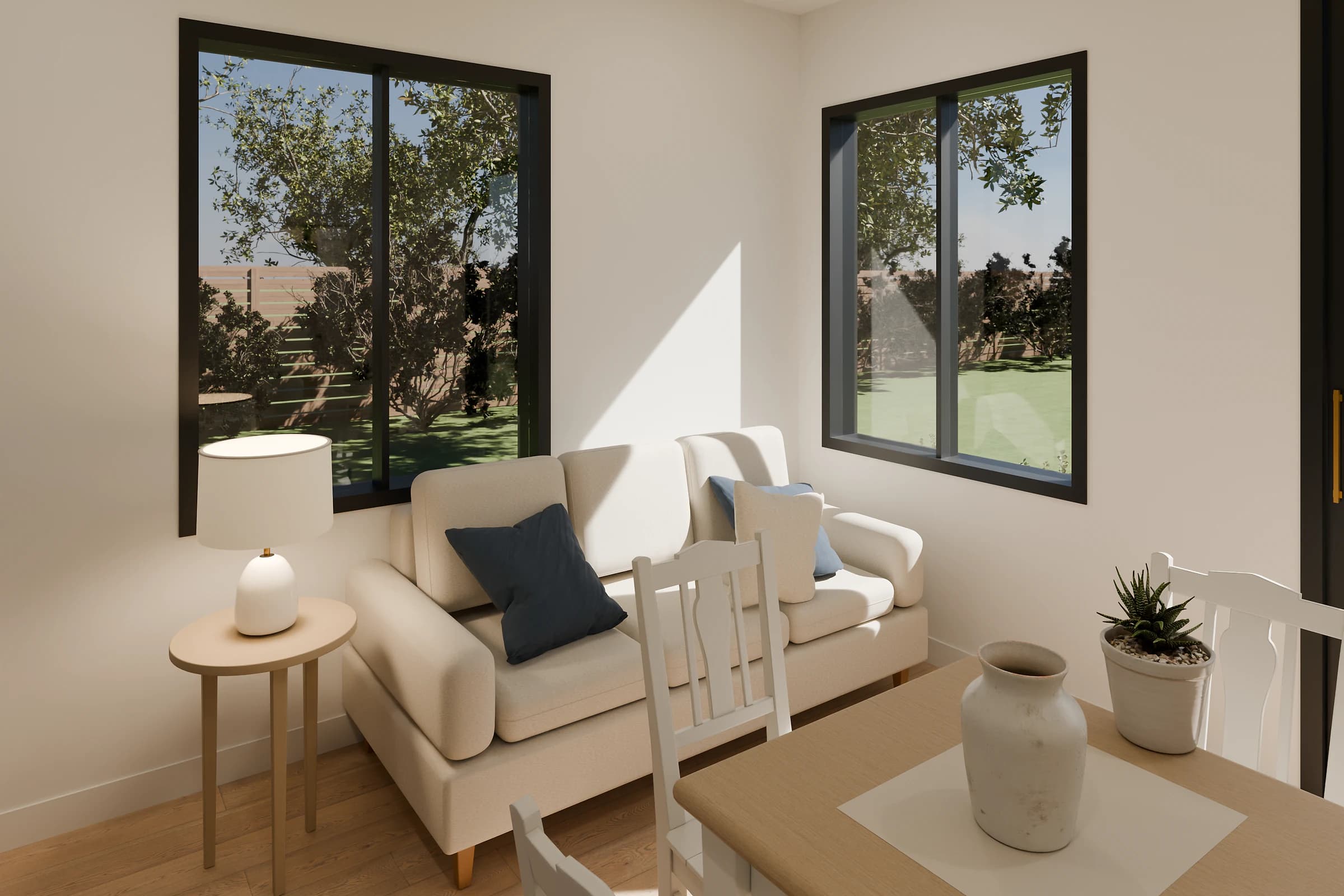 Rendering of the Studio ADU living room, a cream sofa with navy and blue pillows below black-framed windows on two walls, a white lamp on a round side table, and a light wood dining table with white chairs in front